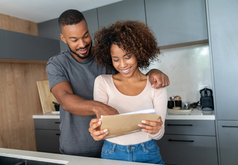Young couple standing together in their kitchen while looking at some documents